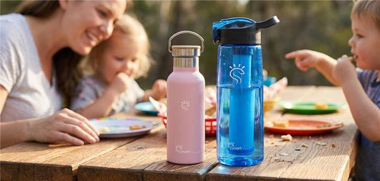 A heartwarming family portrait of a mother receiving breakfast-in-bed from her children, with specific callouts and leader lines highlighting the SmartFlask’s core features: UVC self-cleaning, filtered water, insulation,